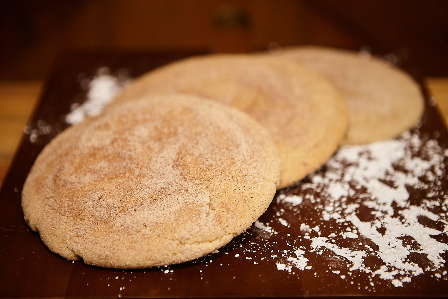 3 freshly baked cinnamon sugar cookies on a cutting board with flour