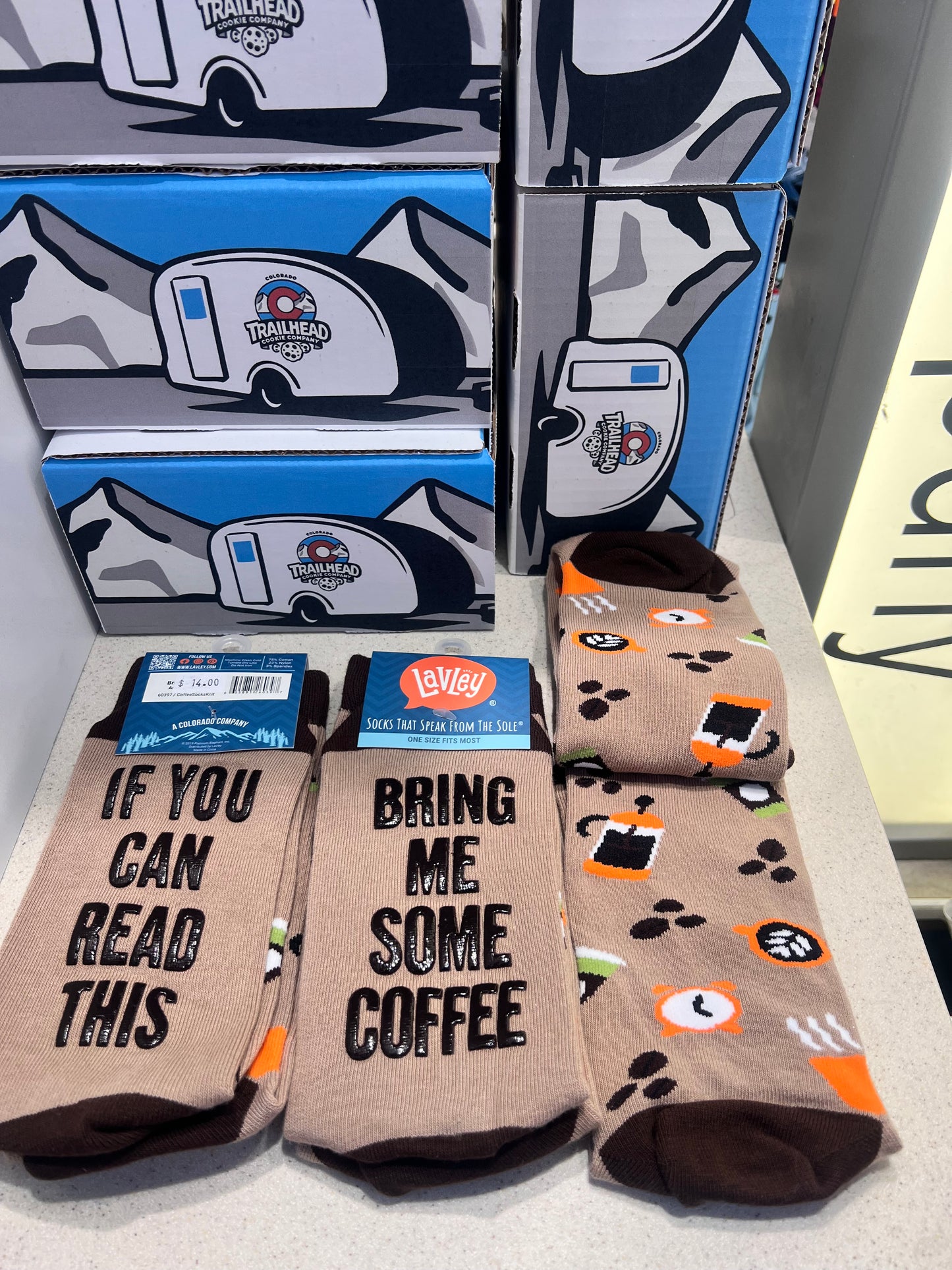 Display of tan novelty socks with different designs with text 'if you can read this bring me coffee'