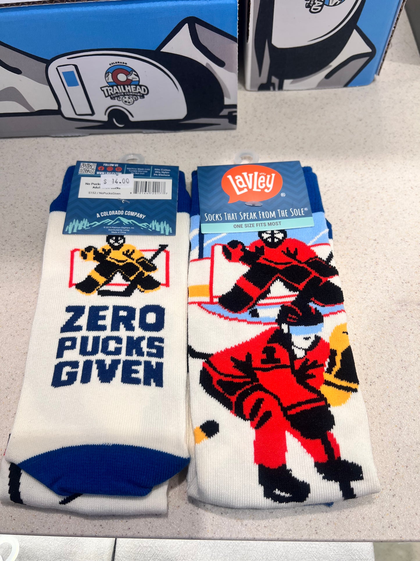 Colorful socks with graphic hockey game and goalie designs and text "zero pucks given"