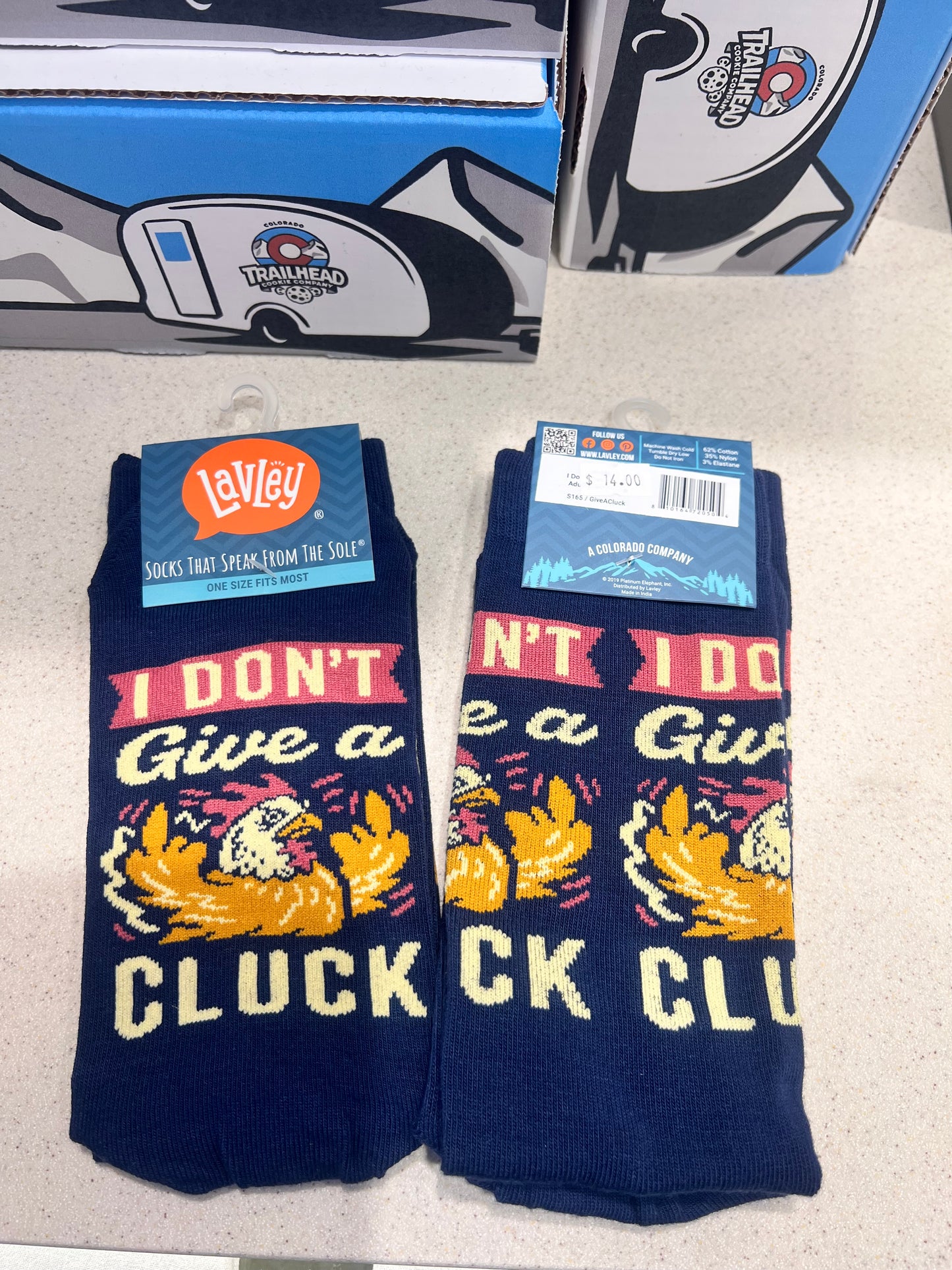 Pair of socks with graphic design of a chicken and text "I don't give a cluck" on a light gray surface