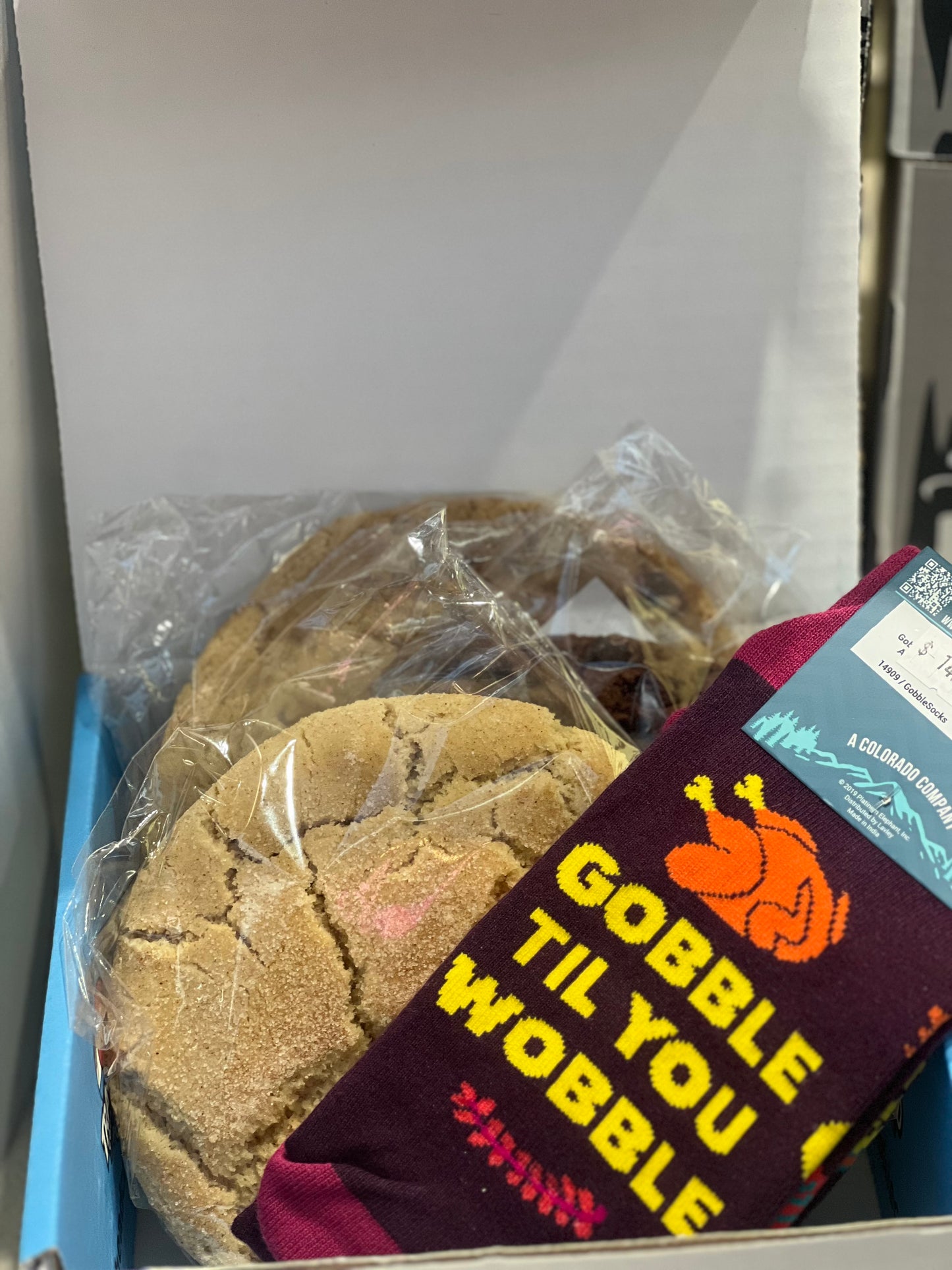 Box containing cookies and a pair of thanksgiving socks with text 'Gobble Til You Wobble'.