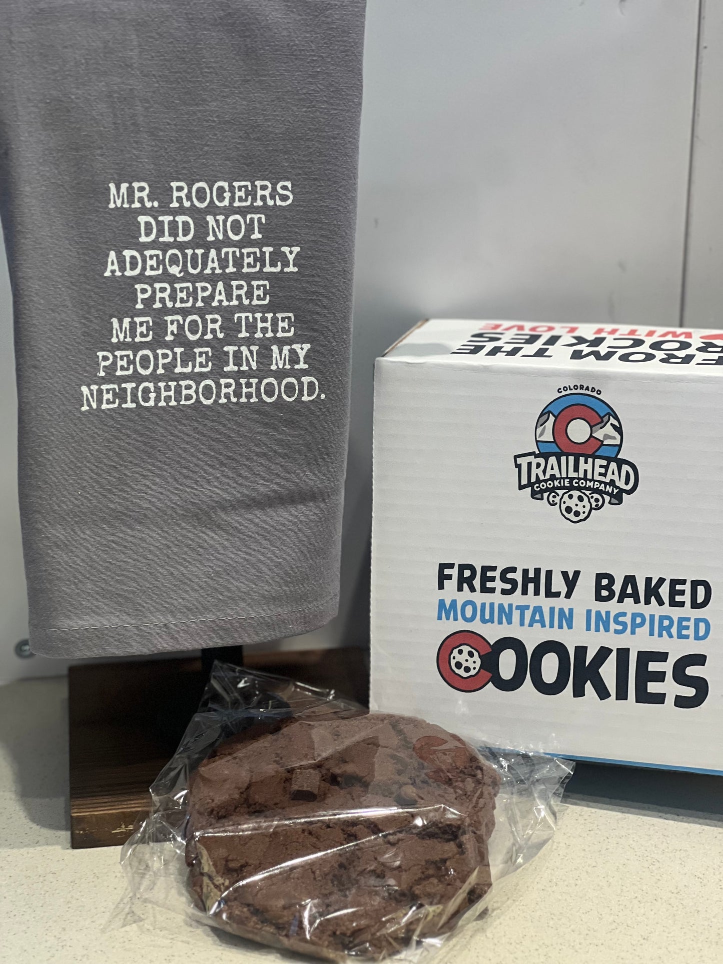 Gray towel with text, box of cookies, and single cookie on a surface