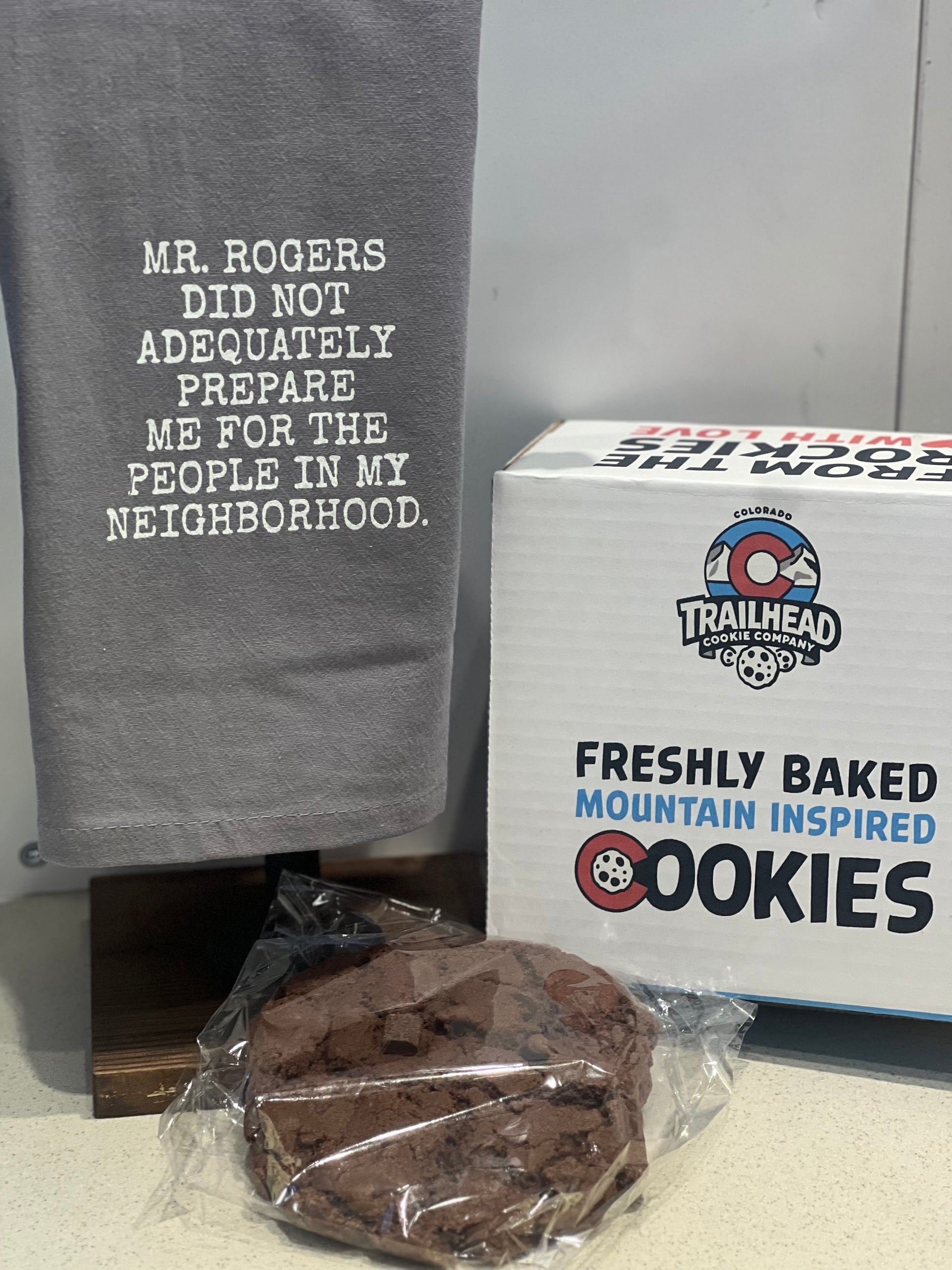 Gray towel with text, box of cookies, and single cookie on a surface