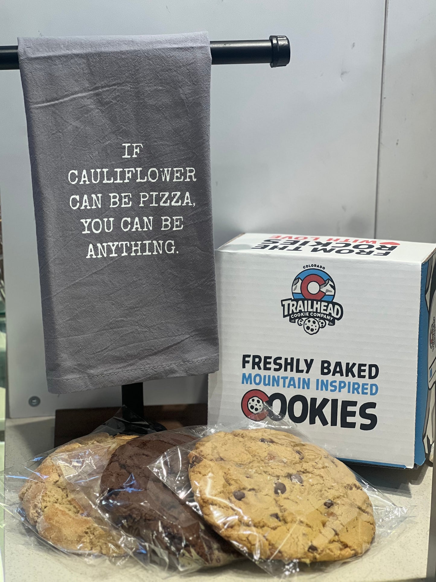 Gray towel with motivational quote, box of cookies, and cookies on a surface.