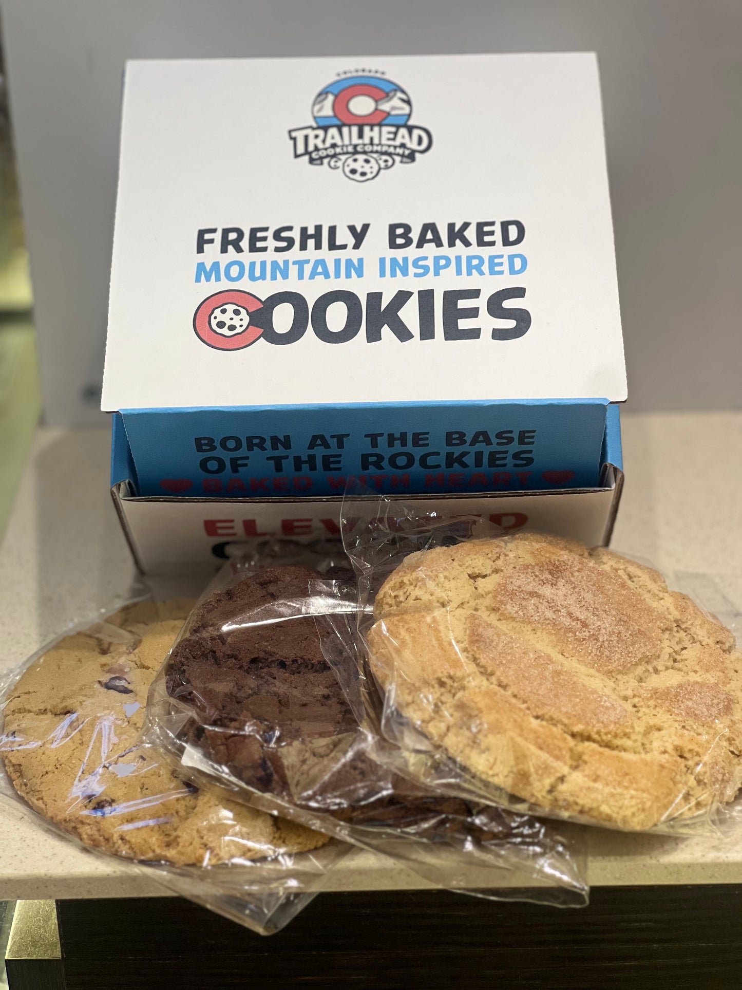 3 large freshly baked cookies in front of a gift box that says freshly baked mountain inspired cookies