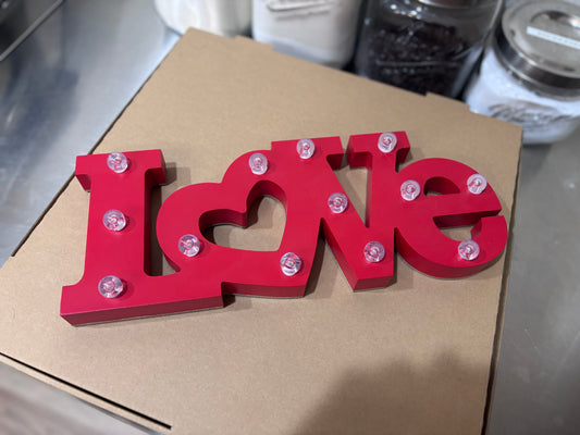 Red 'I Love' sign with small lights on a cardboard box